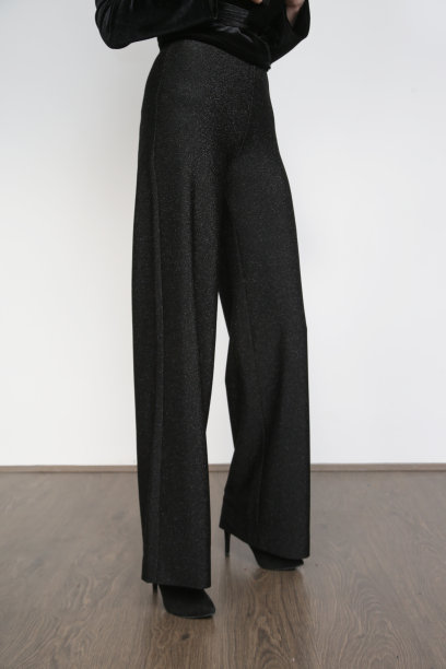 系列工作室照片的女模特穿着宽黑色优雅的裤子和黑色高跟鞋。图片下载