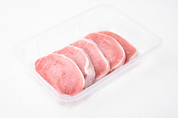 生猪排，塑料包装容器，白色石桌背景，有文字复制空间图片下载