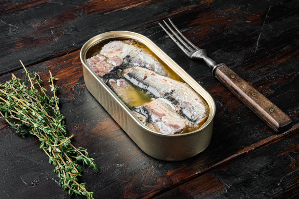 旧的深色木桌背景上放着沙丁鱼罐头蜜饯图片下载