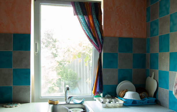 厨房台面上放着一套洗干净的盘子，窗户和水槽、厨房桌子、盘子放在架子上图片下载