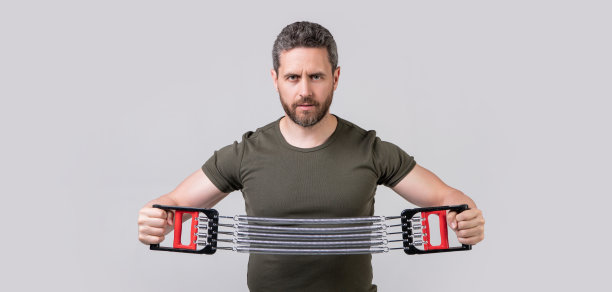 运动员与阻力膨胀隔离在灰色背景。有抵抗力的运动员图片下载