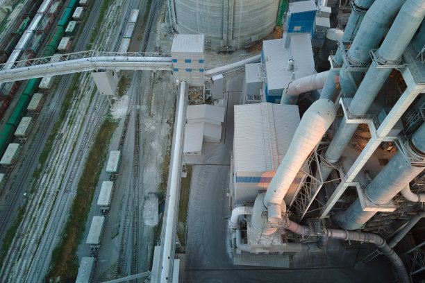 工业生产区具有高厂房结构和塔式起重机的水泥厂。制造和全球产业理念图片下载