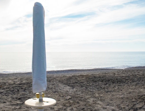 意大利圣玛丽亚德尔塞德罗，以沙滩和大海为背景的折叠沙滩伞。度假酒店。旅游旺季结束的概念图片下载