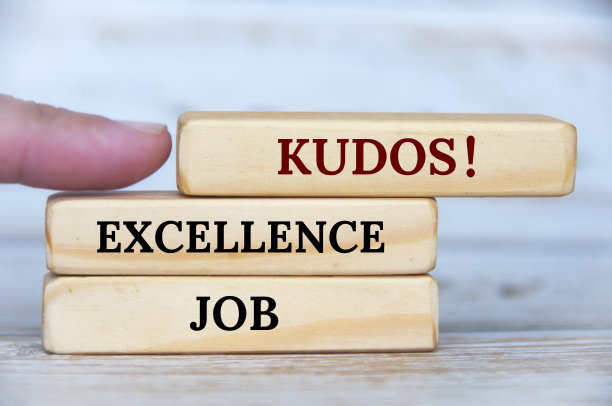 手指指向KUDOS文本的木块与木制封面背景。成就的概念图片下载
