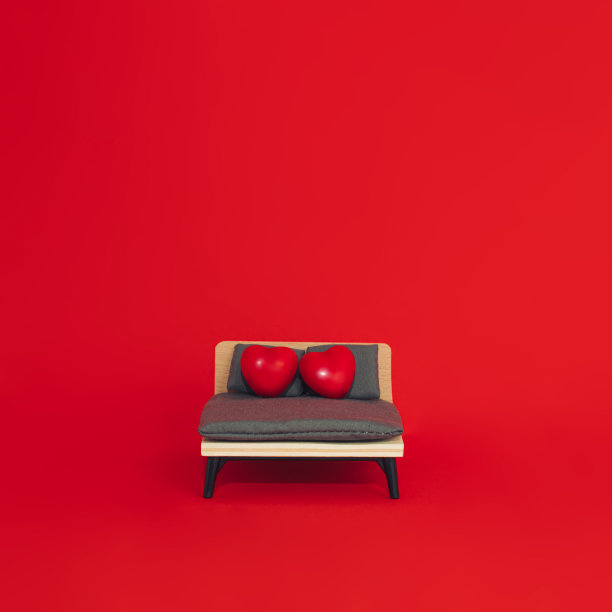 创意的七八十年代复古时尚美学的爱的概念。极简浪漫的想法。床上有两颗红心，背景是鲜艳的红色。爱情还是情人节作文。图片下载