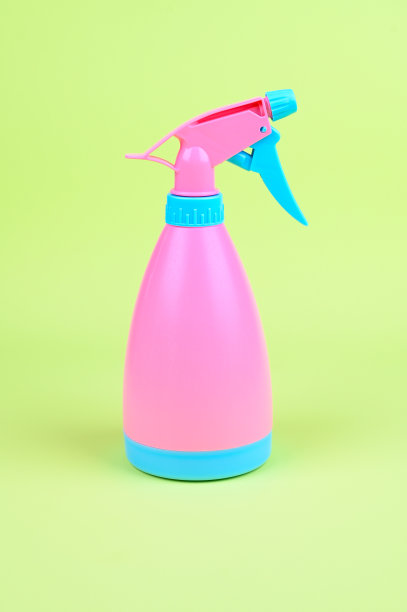 亮粉色清洁喷雾器在绿色背景。粉红色的花园洒水车垂直照片图片下载
