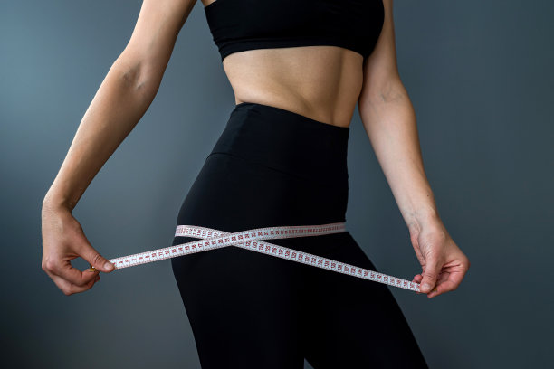 身材健美的女性用卷尺测量腰围，节食后孤立过灰图片下载