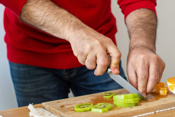 穿着红色衬衫的男人在阁楼厨房烹饪美味健康的食物。准备水果沙拉。垂直的照片。美食摄影概念。图片下载