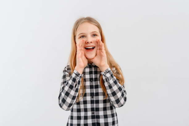 快乐的少女喊和尖叫用她的手管，穿着休闲的格子衬衫，站在白色背景图片下载