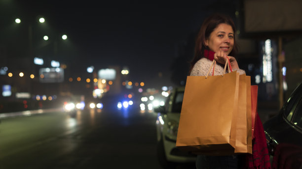 年轻女子购物在晚上背着购物袋图片下载