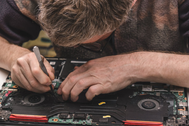 电脑维修技术员将笔记本电脑冷却系统从机箱中取出进行清洁和维护。关闭了。图片下载