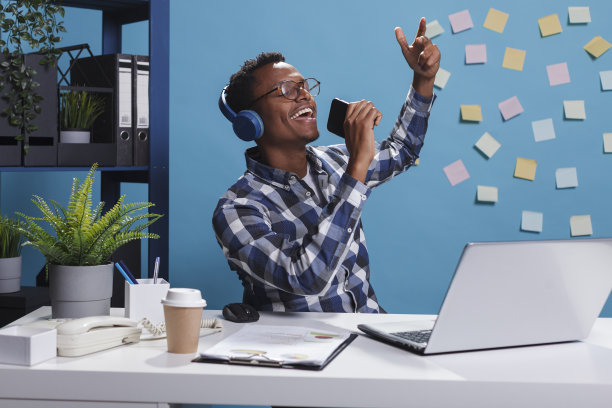 放松的公司员工坐在办公空间唱卡拉ok。图片下载