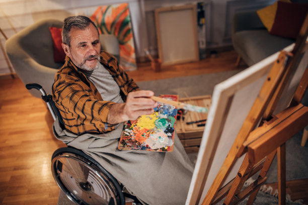 一名坐在轮椅上的男子在画室的画布上作画图片下载