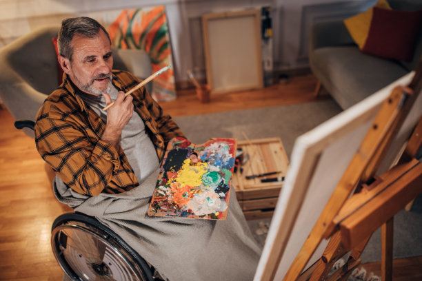 一名坐在轮椅上的男子在画室的画布上作画图片下载