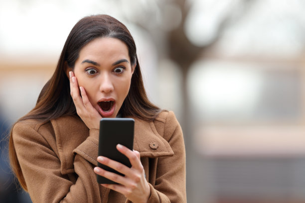 惊奇的女人在冬天查看手机图片下载