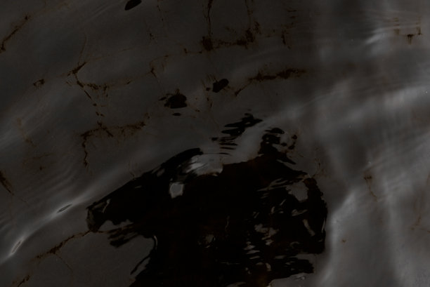 黑白照片的纹理的表面运动的水波和阴影的反射在底部。背景是阴郁的。图片下载