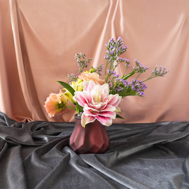 一幅静止的自然构图，由一朵兰花和一些野花组成，镶嵌在深棕色的花瓶里，背景是灰色和米色的织物。情人节或婚礼卡片设计的豪华概念。图片下载