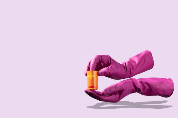 紫色手套拿着一个大的橙色电池在浅紫色的背景图片下载