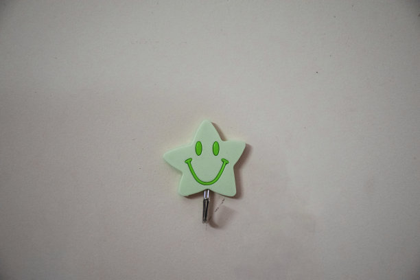 绿色微笑星形墙贴衣架用于挂东西的库存照片，贴衣架安装或贴在淡黄色油漆的墙上，图片拍摄于印度海得拉巴。图片下载