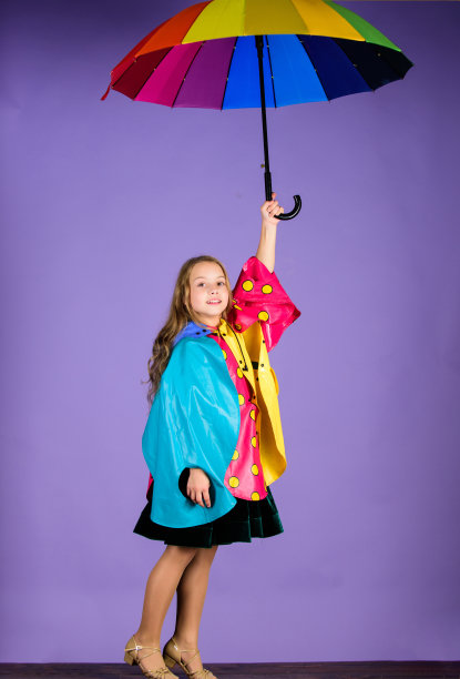 穿着合适的衣服享受雨天。防水配件让雨天变得愉悦。儿童防水配件。孩子，女孩，快乐地撑着彩色伞，穿防水斗篷图片下载