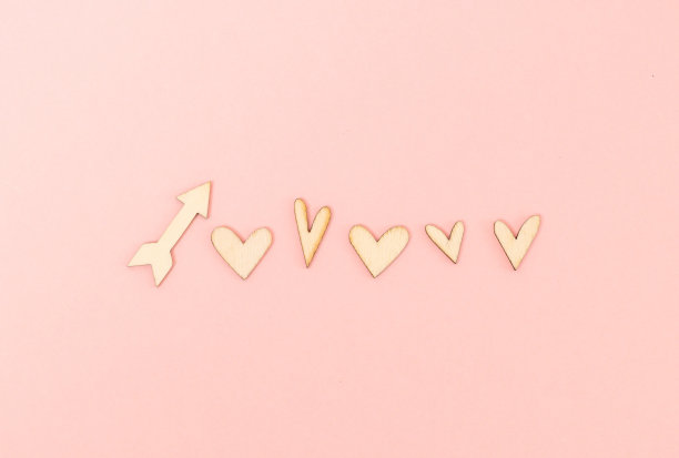 粉色背景上的木制心形和箭头。图片下载