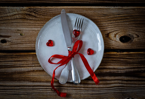 刀，叉，红丝带和盘子上的心形酒杯。图片下载