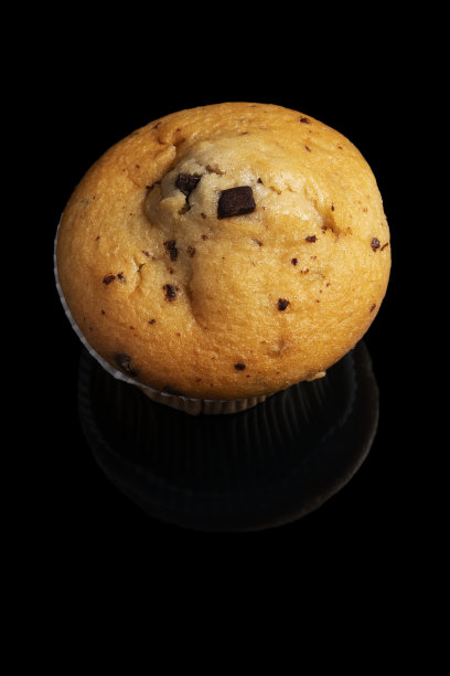 黑色背景上有巧克力片的松饼或纸杯蛋糕。制作工业或自制糕点的概念。图片下载