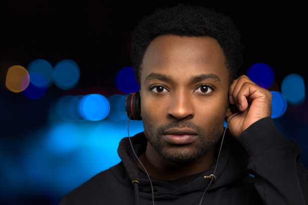 男人在蓝色散景灯背景下戴着耳机听音乐图片下载