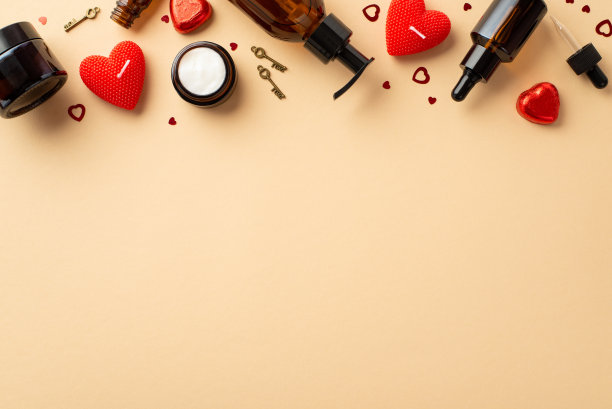 护肤品概念。顶部视图照片琥珀化妆品瓶子红色心形蜡烛巧克力糖果小钥匙和纸屑在孤立的粉彩米色背景与空白图片下载