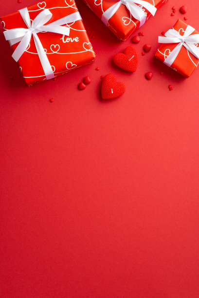 情人节的概念。俯视图垂直照片红色礼盒与白色丝带蝴蝶结心形蜡烛和洒在孤立的红色背景与文案空间图片下载