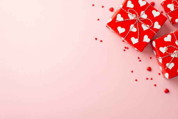 情人节的概念。顶部视图照片的礼盒包装与心形图案和洒在孤立的粉彩粉红色背景与复印空间图片下载