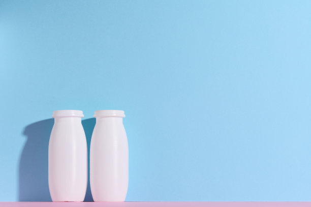 蓝色背景的白色塑料瓶用来装酸奶和乳制品图片下载