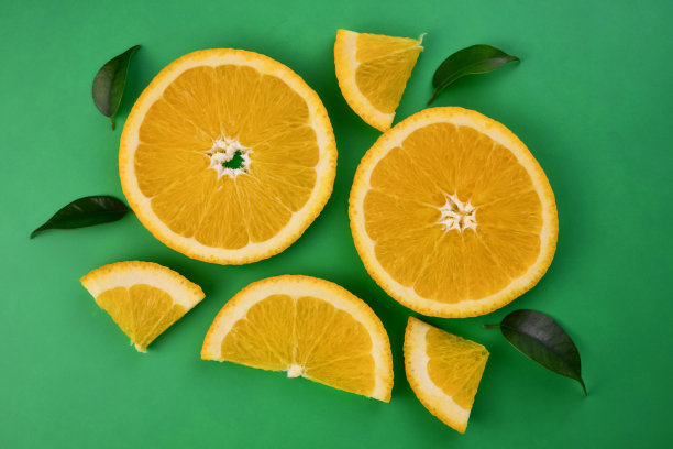 新鲜的橙色柑橘类水果，绿色背景上有叶子。图片下载