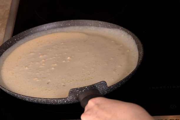 在厨房里用平底锅做薄煎饼的照片，手在相框里图片下载