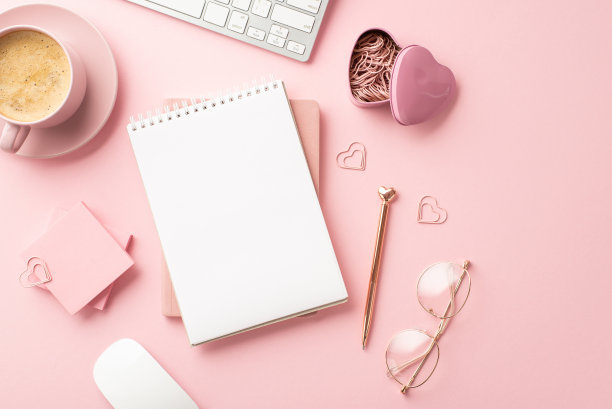 3月8日的概念。顶视图照片文具规划师时尚的钢笔眼镜心形夹子便签纸键盘和杯子的泡沫咖啡在孤立的粉彩粉红色背景与空白图片下载