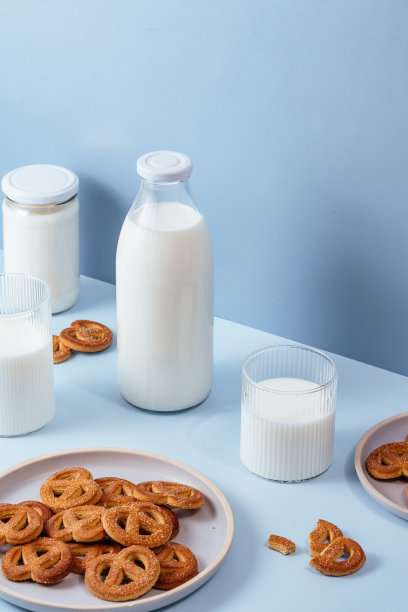 牛奶装在玻璃杯和瓶子里，饼干装在盘子里。浅蓝色bac图片下载