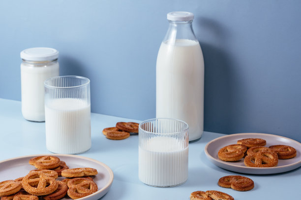 牛奶装在玻璃杯和瓶子里，饼干装在盘子里。浅蓝色bac图片下载