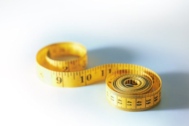 黄色卷尺卷成螺旋形，缝纫工具或减肥饮食符号，浅灰色蓝色背景与复制空间，选定的焦点图片下载