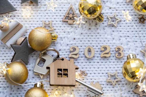 房子钥匙与钥匙链小屋节日针织背景与星星，灯的花环。2023年新年快乐，木函，贺卡。购买、建造、搬迁、抵押图片下载