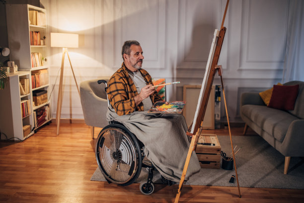 一位坐在轮椅上的残疾人在工作室的画布上作画图片下载