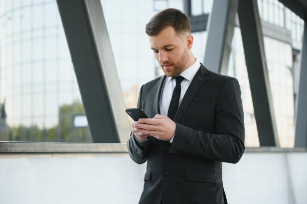 自信的年轻商人在城市中使用手机。图片下载