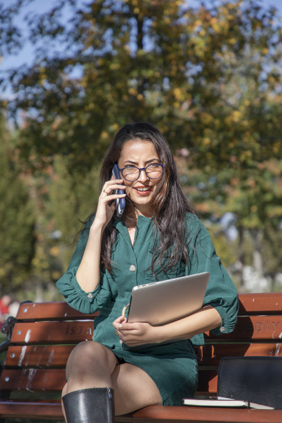 年轻美丽的女子在秋天落叶工作与她的电脑图片下载