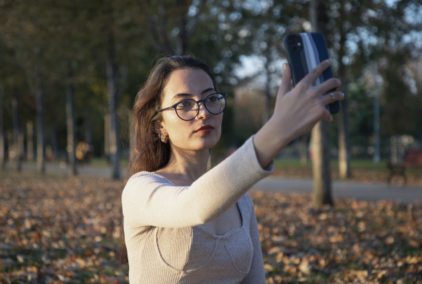 年轻美丽的女子在秋叶自拍图片下载