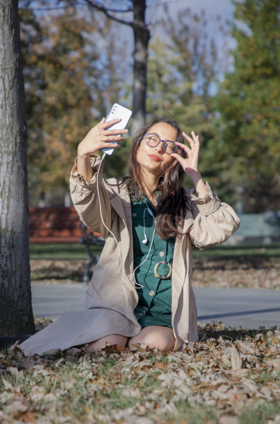年轻美丽的女子在秋叶自拍图片下载