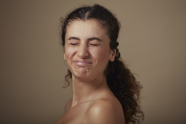 年轻女子的肖像闭上眼睛，做鬼脸。图片下载