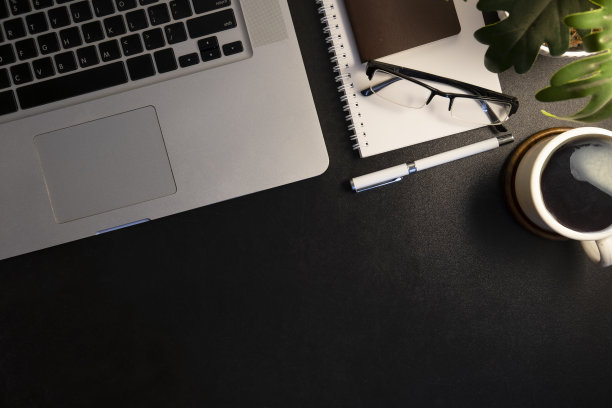 黑色工作台，配有无线键盘，眼镜，记事本和咖啡杯。带有复制空间的俯视图。图片下载