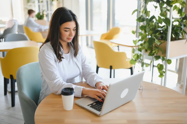 美丽的白人女子梦想着什么，坐在现代咖啡馆酒吧的便携式上网本，年轻迷人的女性自由职业者在笔记本电脑上工作时思考新想法图片下载