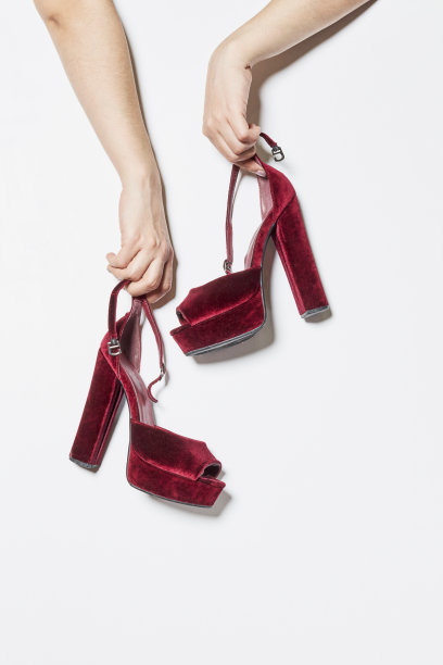 女子手持白色背景上的时尚高跟鞋。特写女性明亮的夏季鞋。购物与时尚图片下载