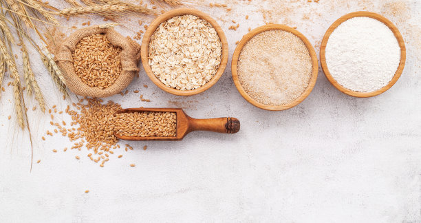 麦粒，黑麦粉和白麦粉放在木碗里，背景是白色的混凝土。图片下载