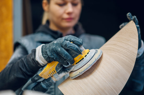 在车间或工厂使用电动砂光机的女木匠图片下载